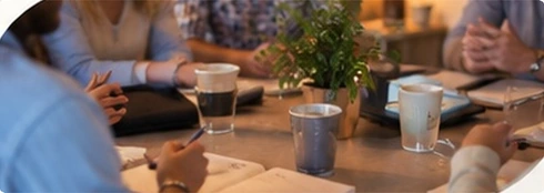 Illustrative scene: people reflecting together around a table with notebooks